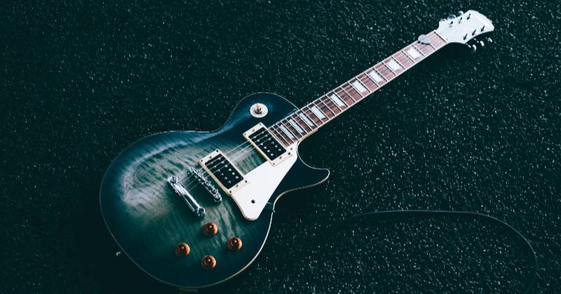 An electric guitar siting on pavement in dim light.